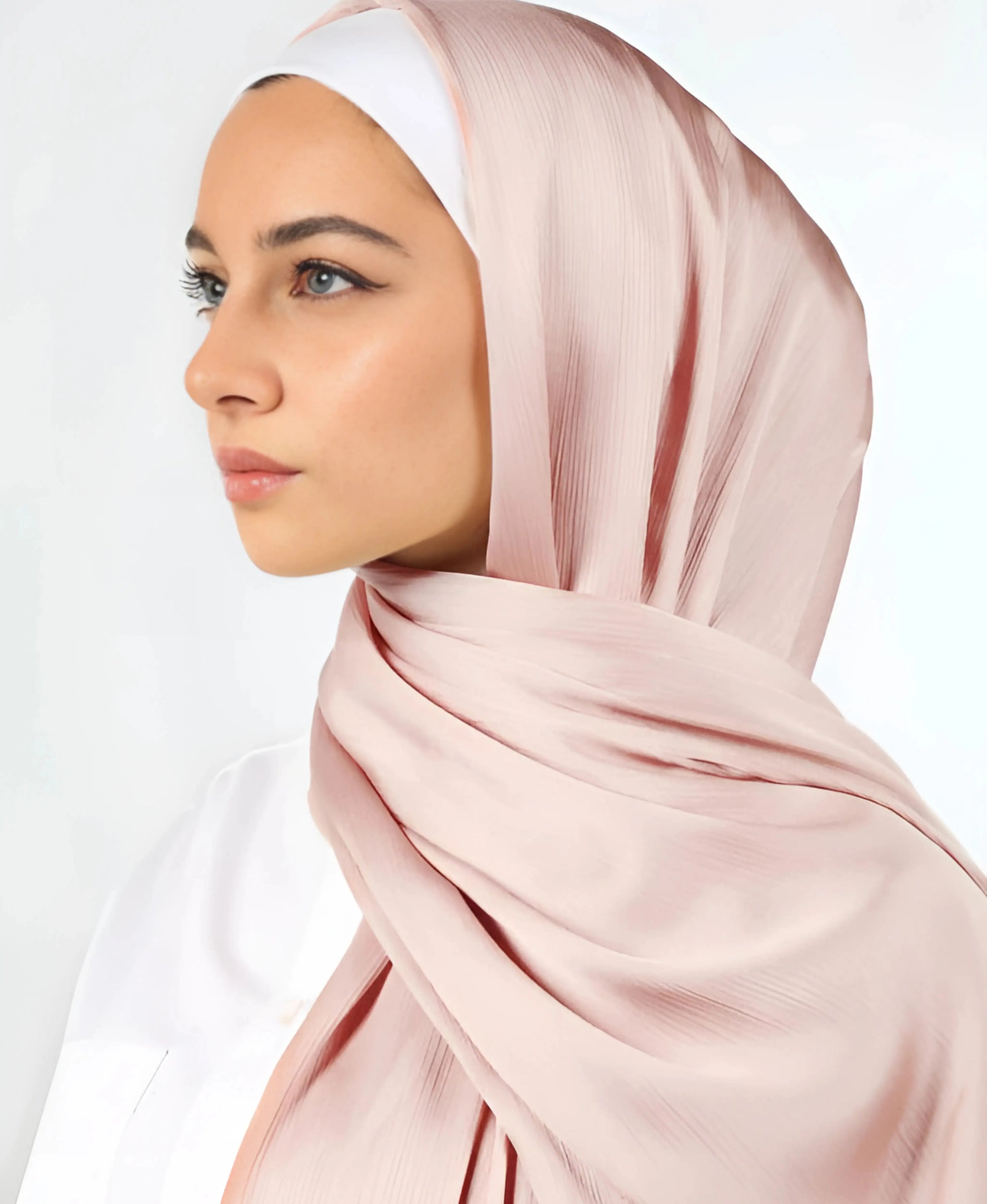 Woman wearing a light pink hijab on a white background
