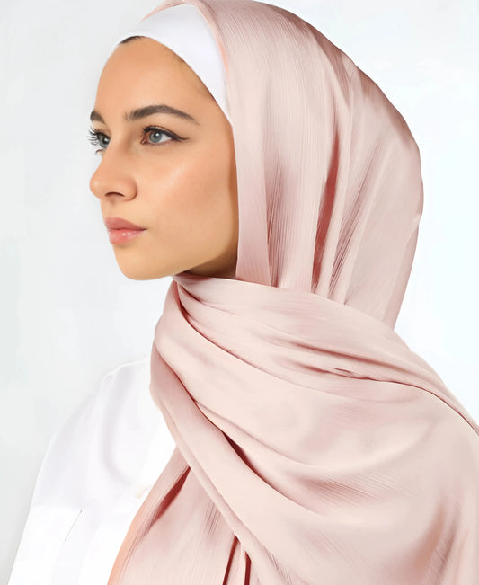 Woman wearing a light pink hijab on a white background