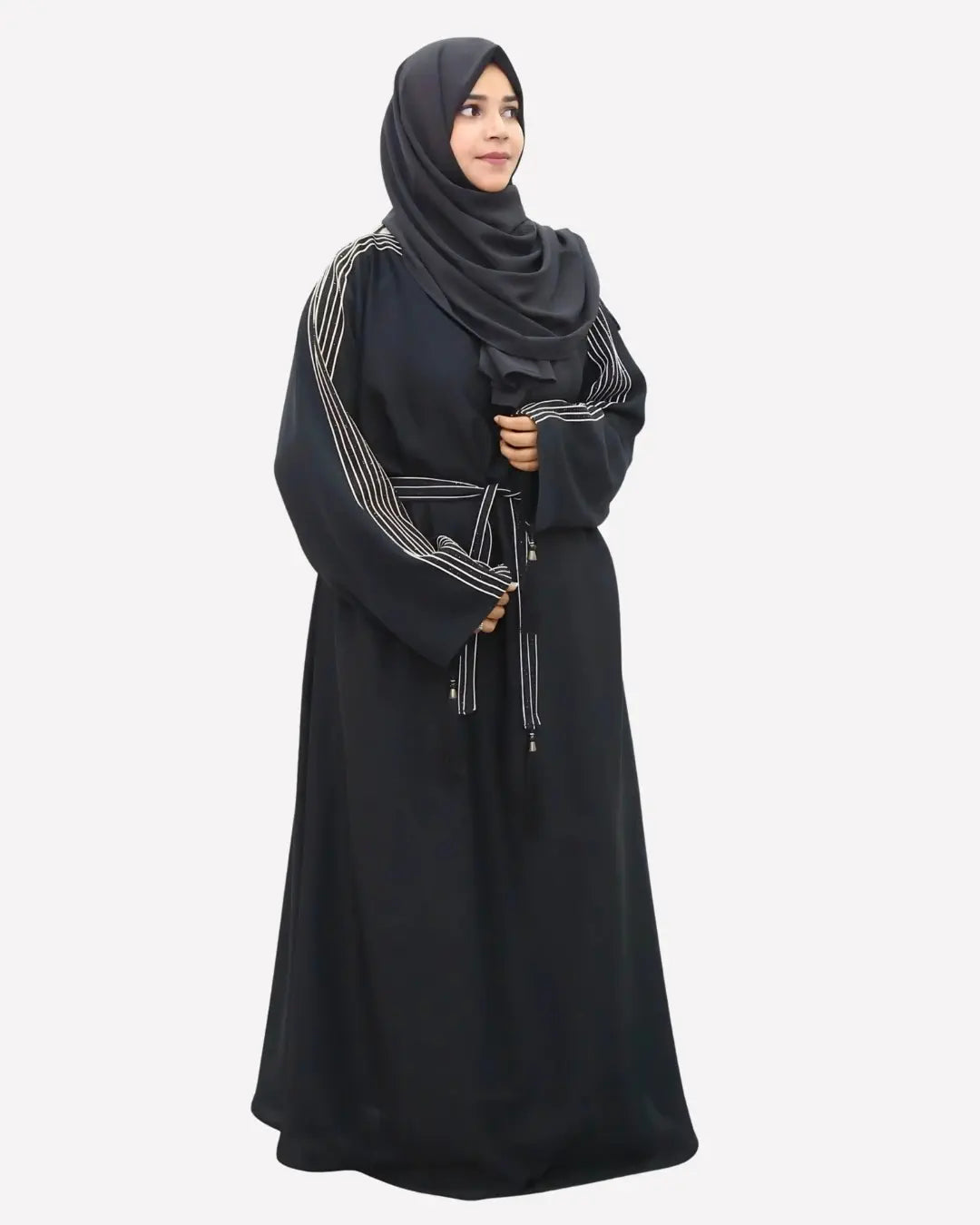 Woman wearing a black abaya with white embroidery on a white background