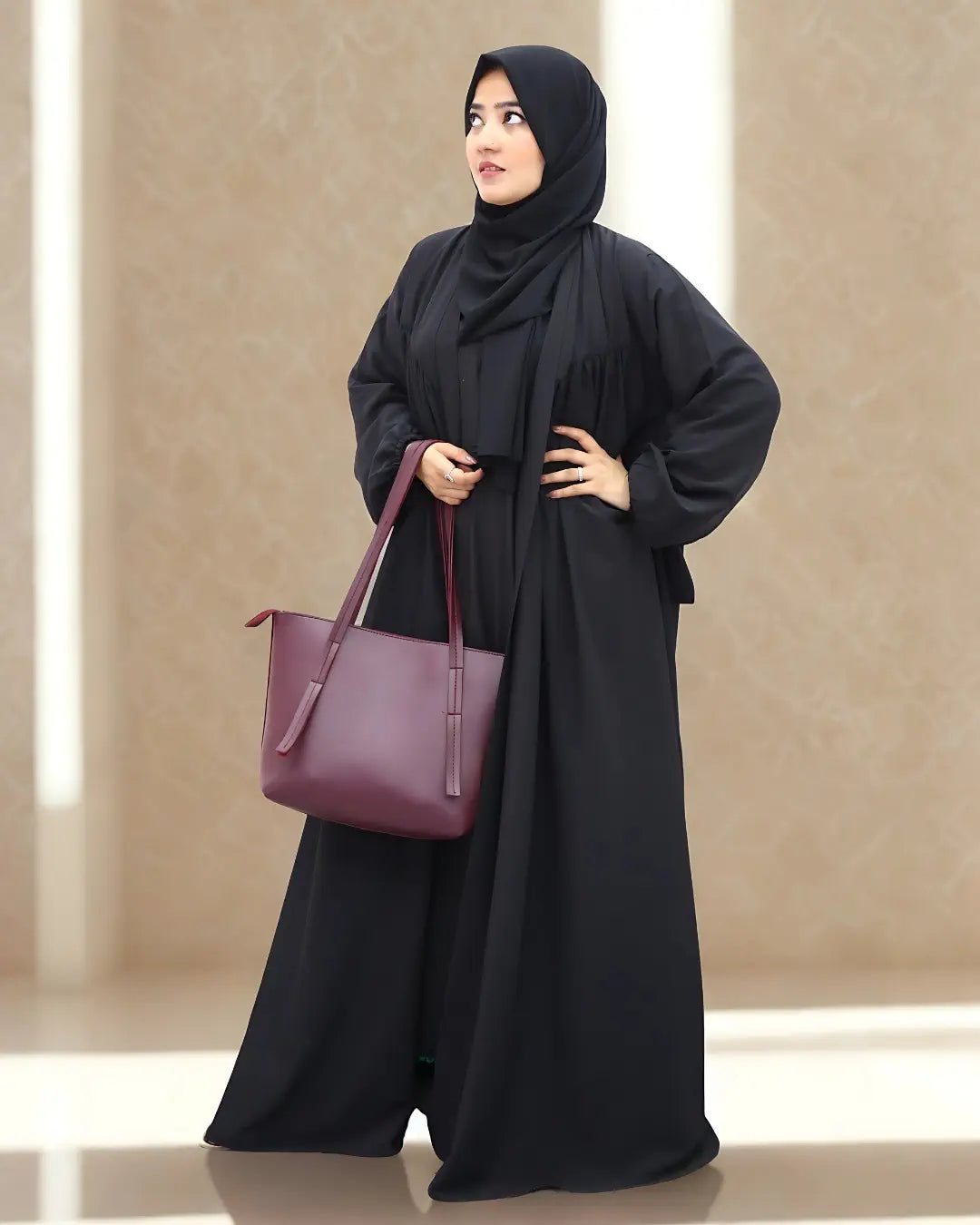 Woman in a black abaya holding a purple handbag against a beige background