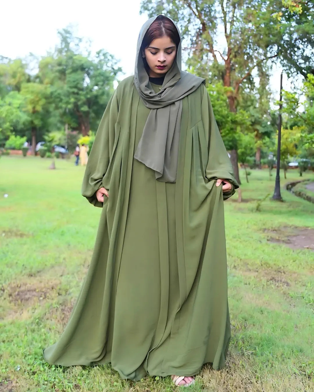 Woman wearing a green abaya in a park setting