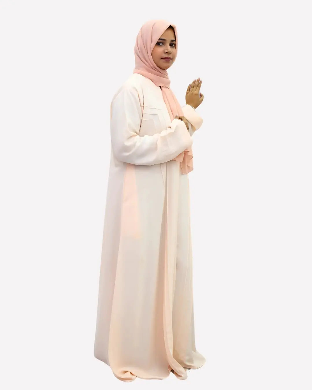 Woman wearing a long, light-colored abaya with a matching hijab on a white background