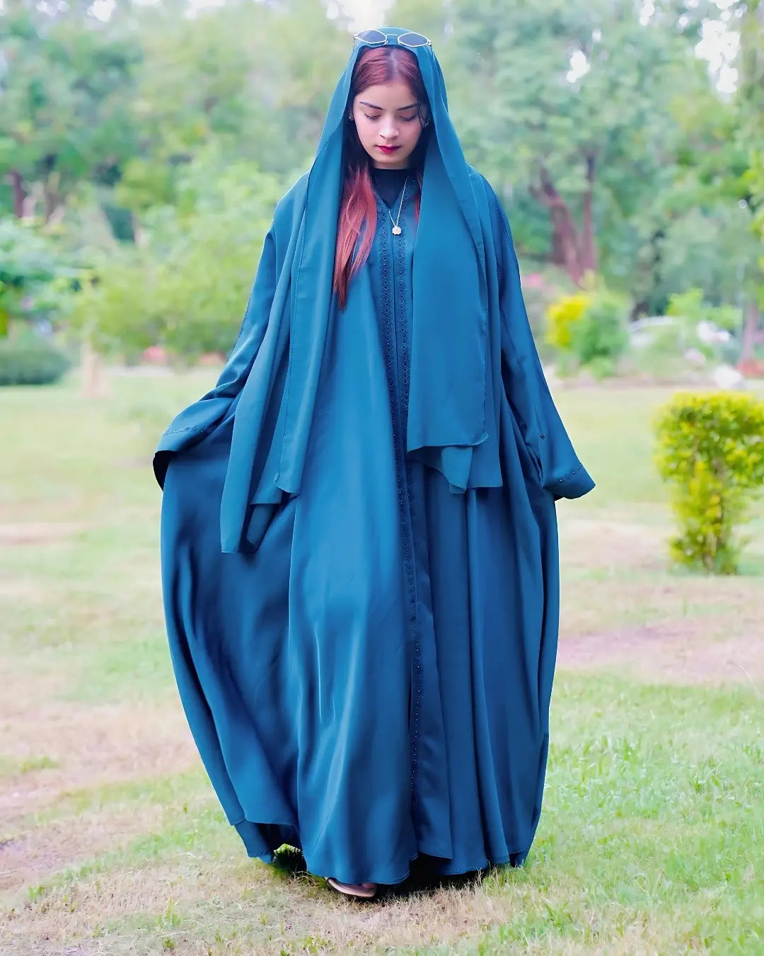 Person wearing a teal abaya in a park setting