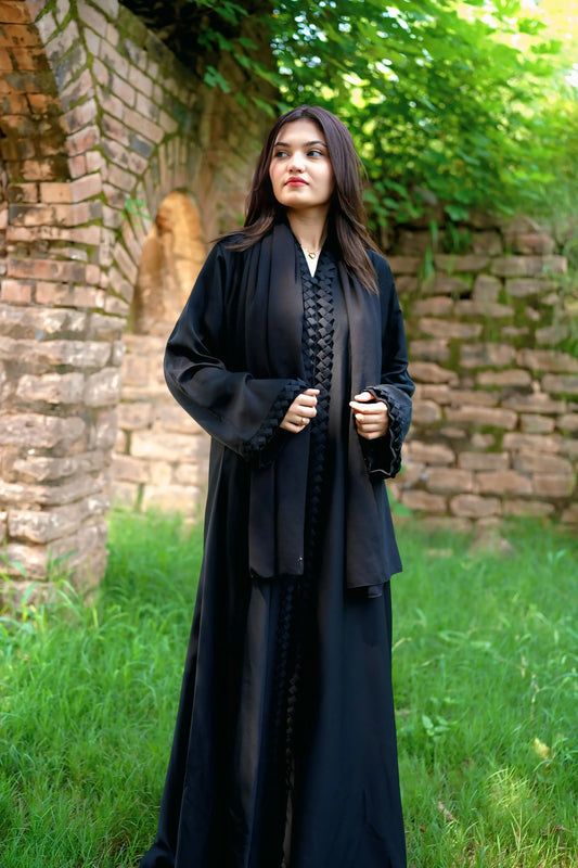 Elegant young woman wearing a black abaya and hijab, showcasing modest fashion style.