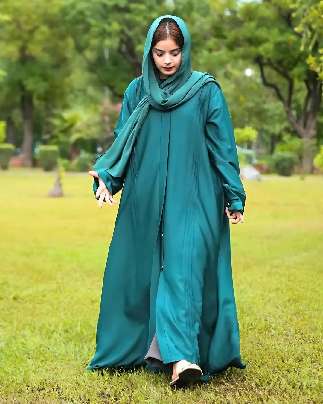 Woman wearing a teal abaya in a park setting