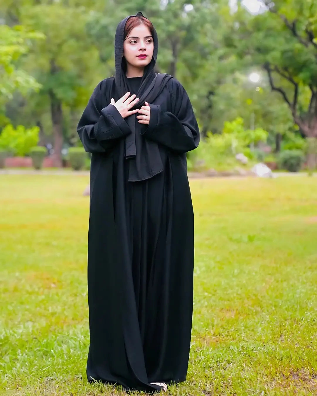Person wearing a black abaya in a park setting