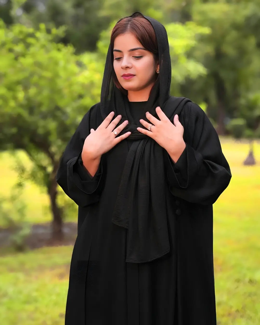 Person wearing a black abaya in a park setting
