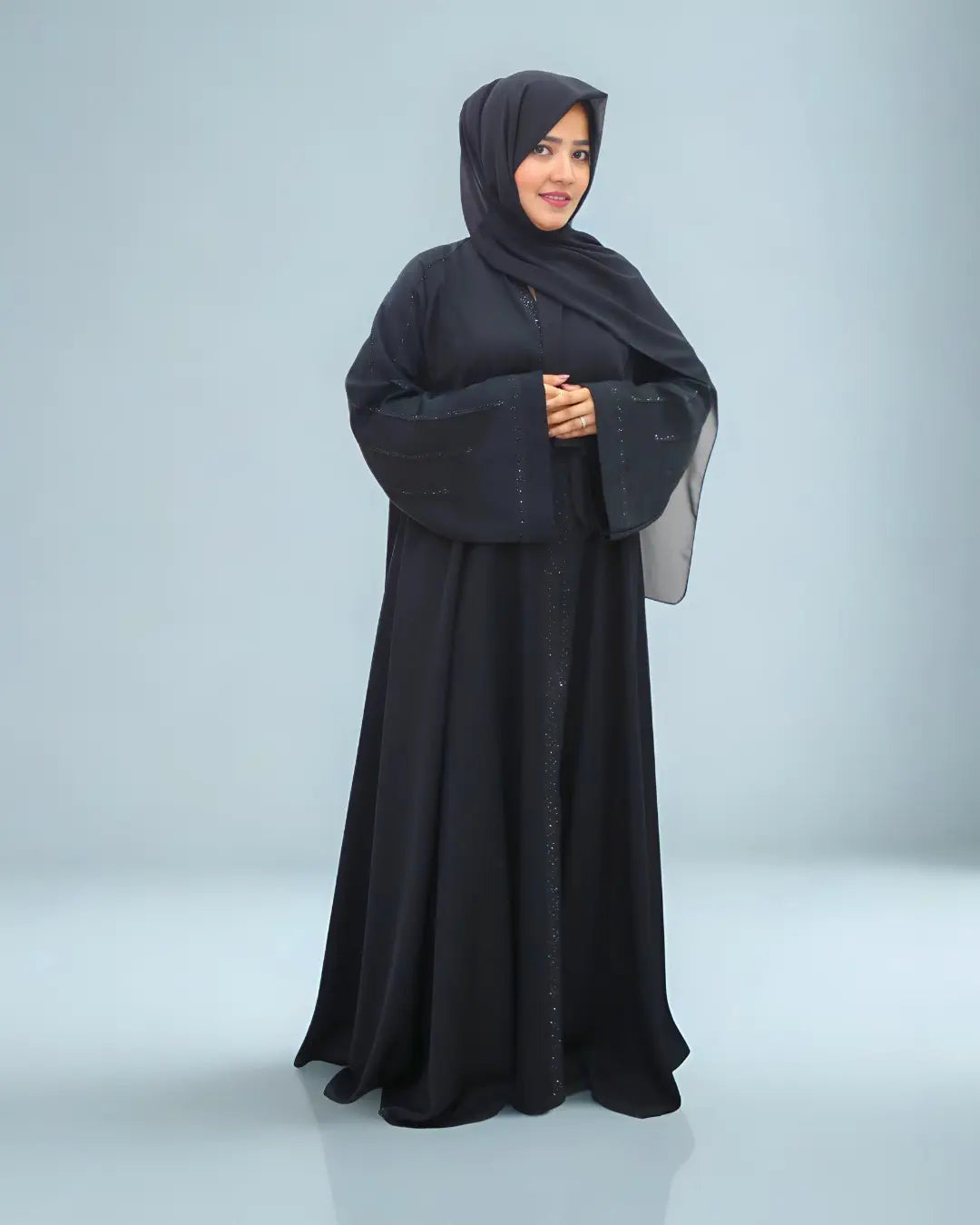Woman wearing a black abaya on a light gray background