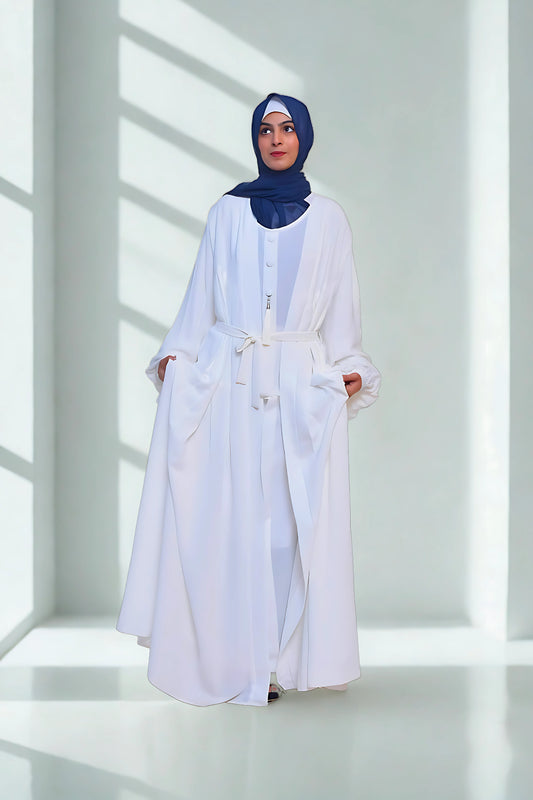 A girl in an Abaya with hijab standing in room with grey background