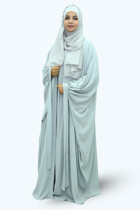 Woman wearing a light blue abaya and hijab on a white background