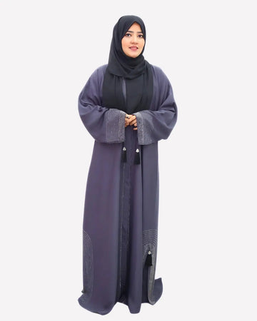 Woman wearing a long, dark gray abaya with a matching hijab on a white background
