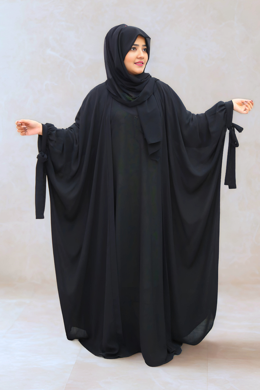 Woman wearing a black abaya with a plain background