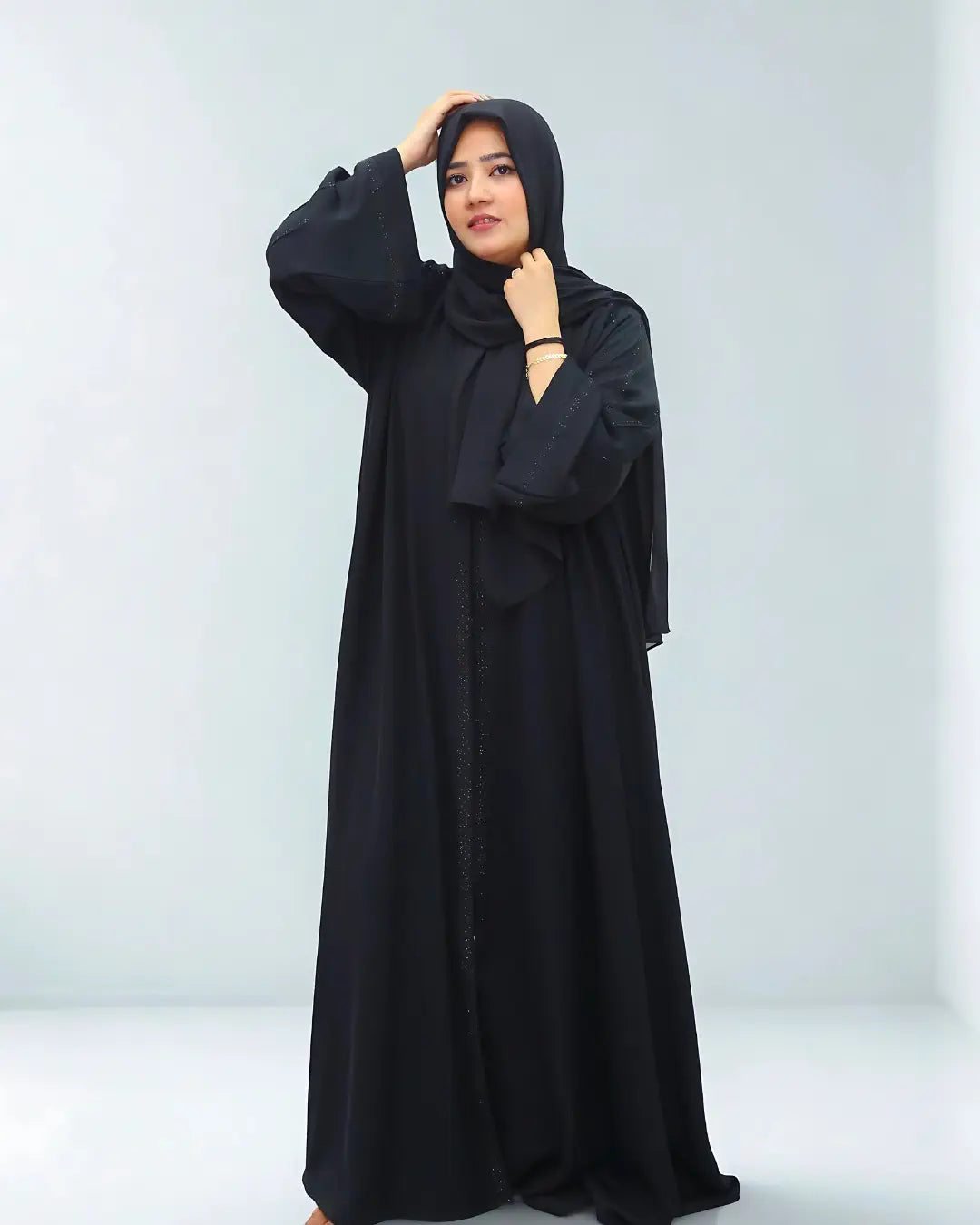 Woman wearing a black abaya against a white background