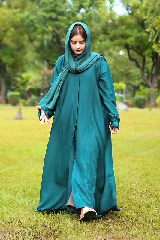 A girl wearing a teal abaya and scarf in a park