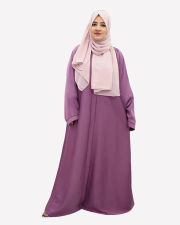 Woman wearing a long purple abaya and pink hijab on a white background
