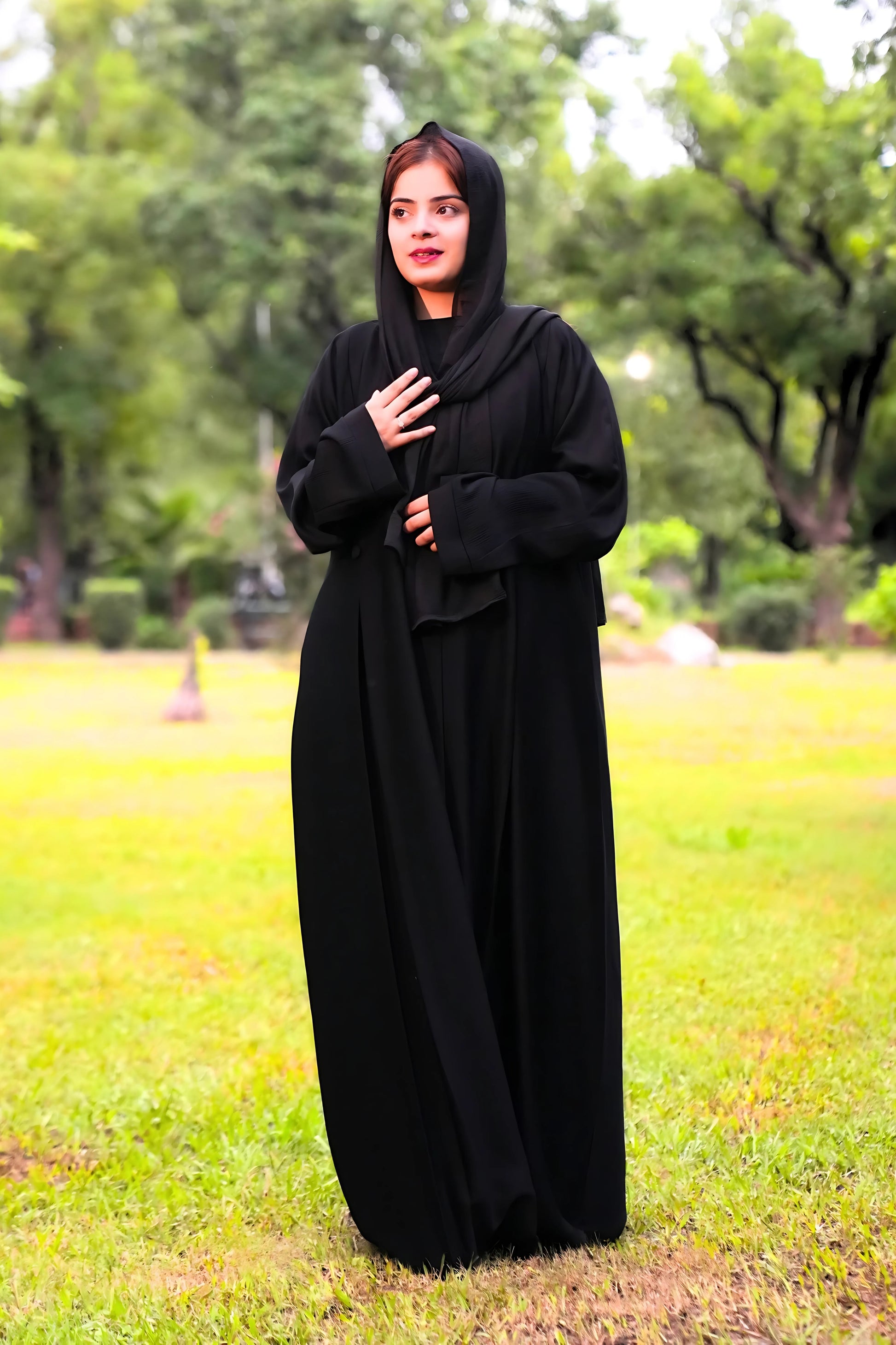 a girl wearing a black abaya in a park setting