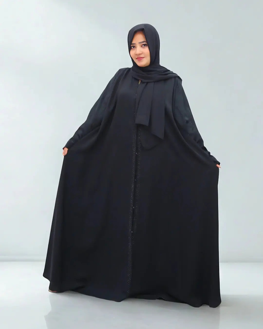 Woman wearing a black abaya on a white background