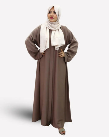 Woman wearing a long brown abaya and white hijab on a white background