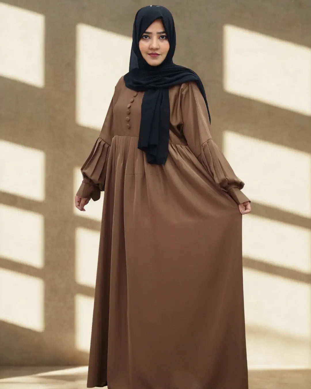Woman wearing a brown abaya with a black hijab in a sunlit room