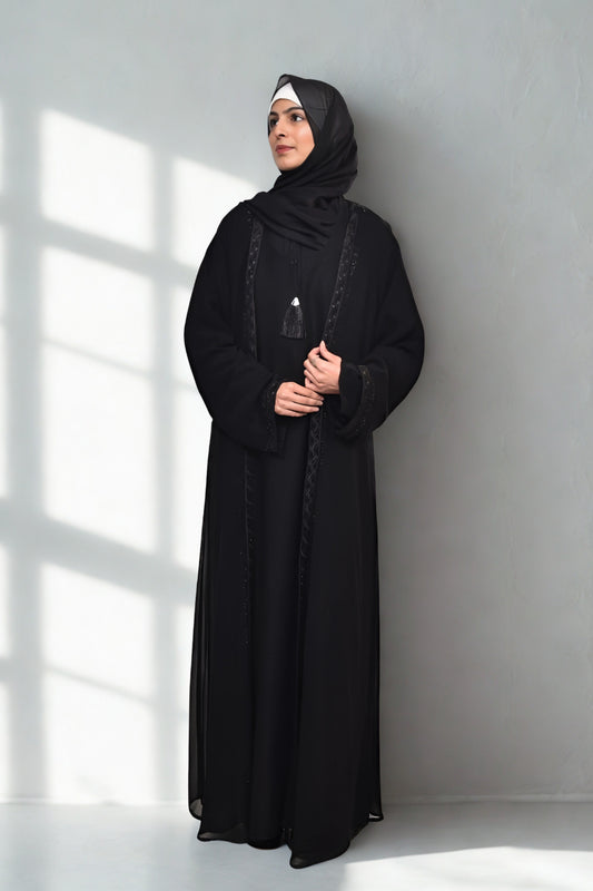 A girl in an Abaya with hijab standing in room with grey background