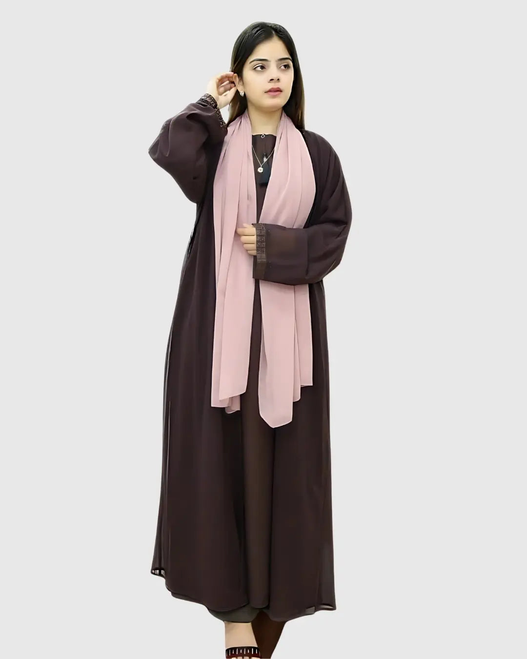 Woman wearing a long brown abaya with a pink scarf on a white background