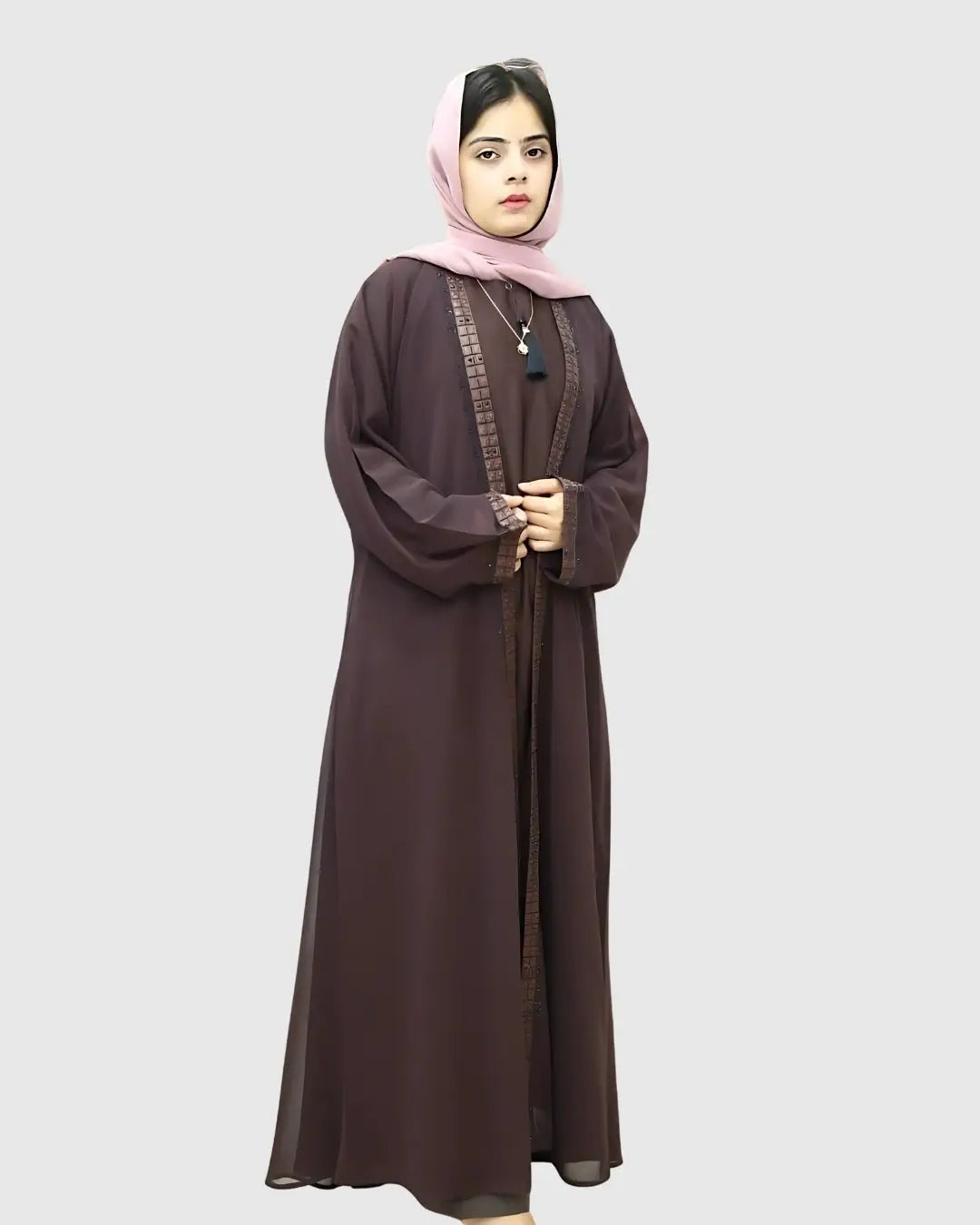 Woman wearing a long brown abaya with a pink scarf on a white background