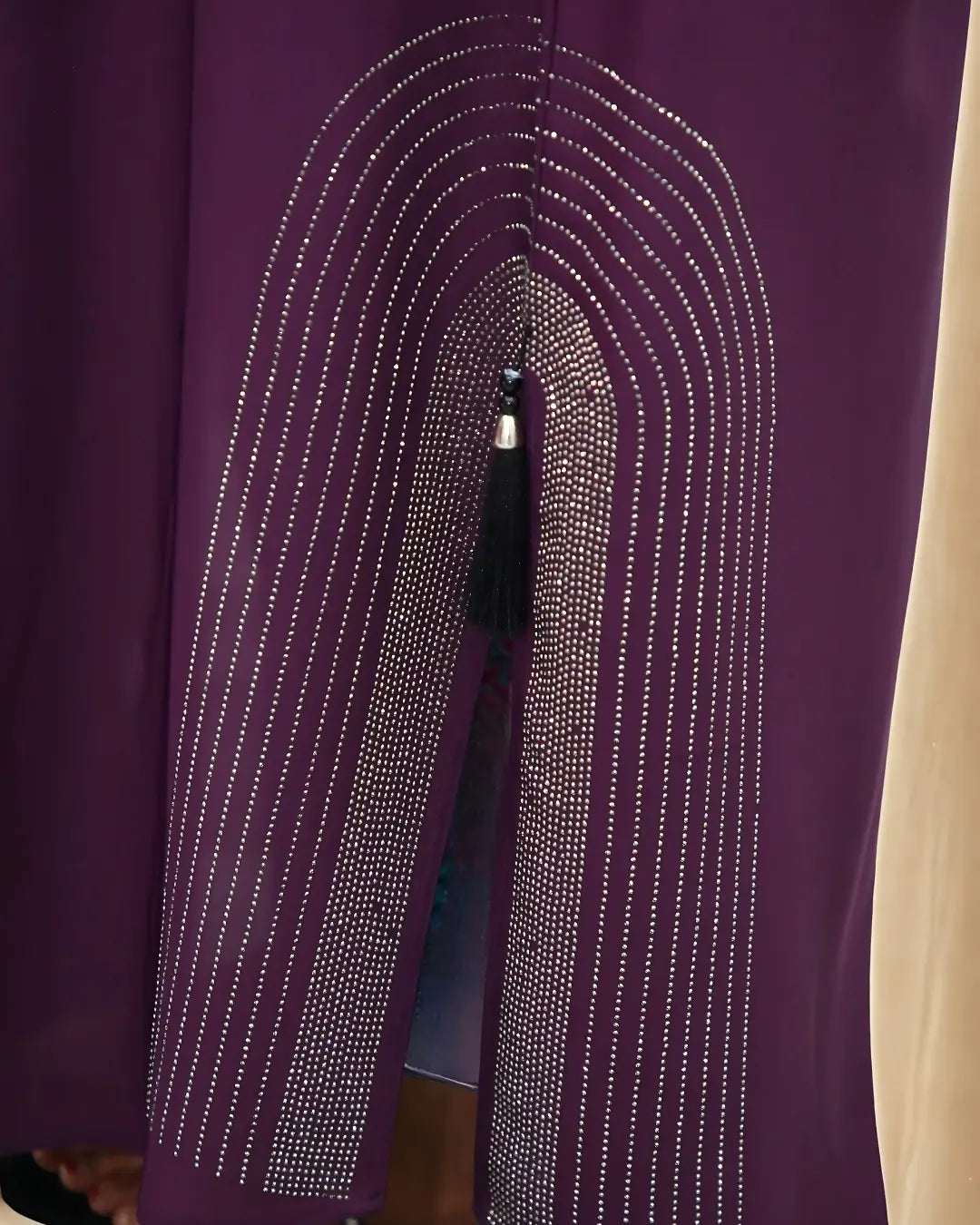 Close-up of a purple garment with decorative stitching and a zipper.