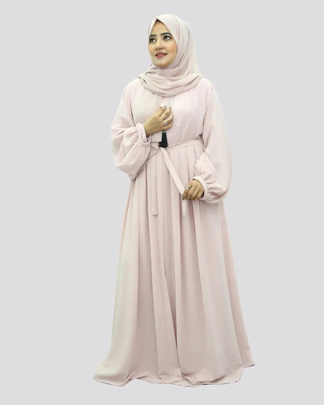 Woman wearing a light pink abaya and hijab on a white background