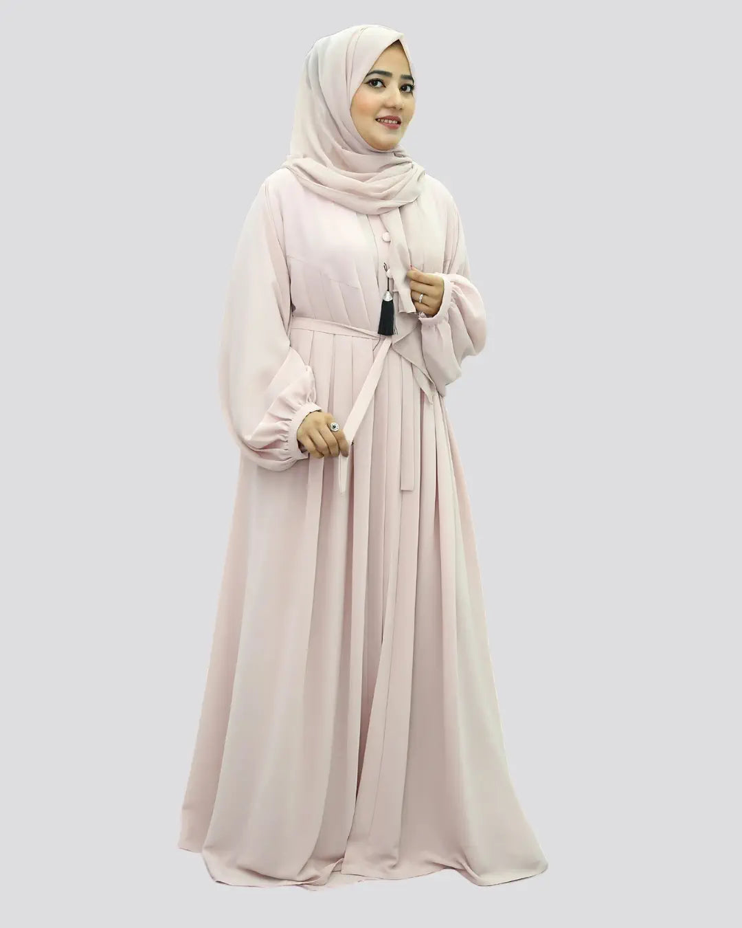 Woman wearing a light pink abaya and hijab on a white background