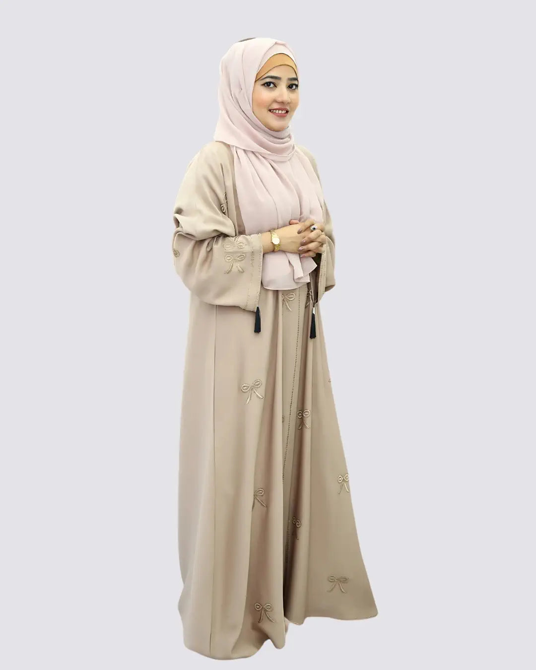 Woman wearing a beige abaya and hijab on a white background