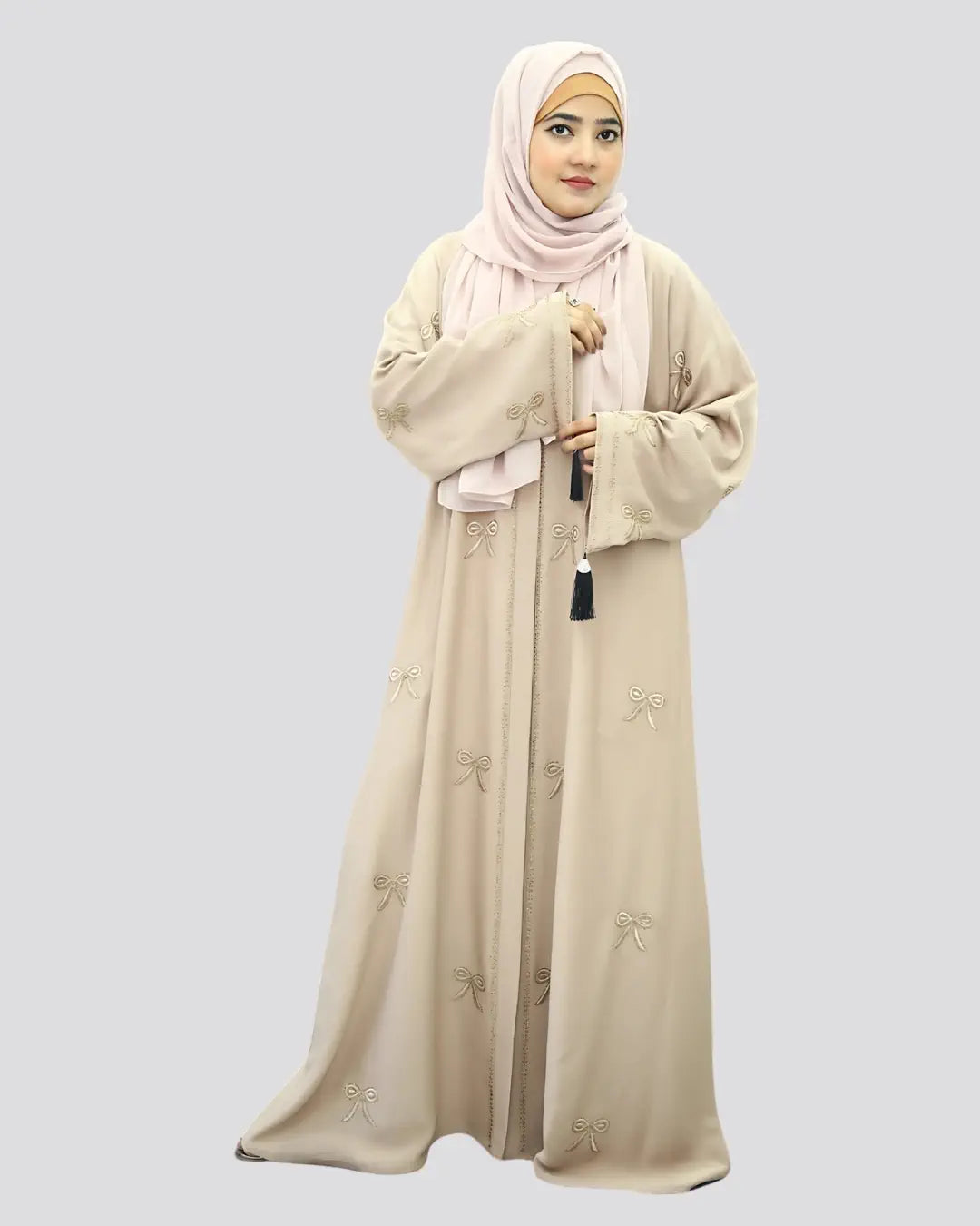 Woman wearing a beige abaya with floral patterns on a light gray background