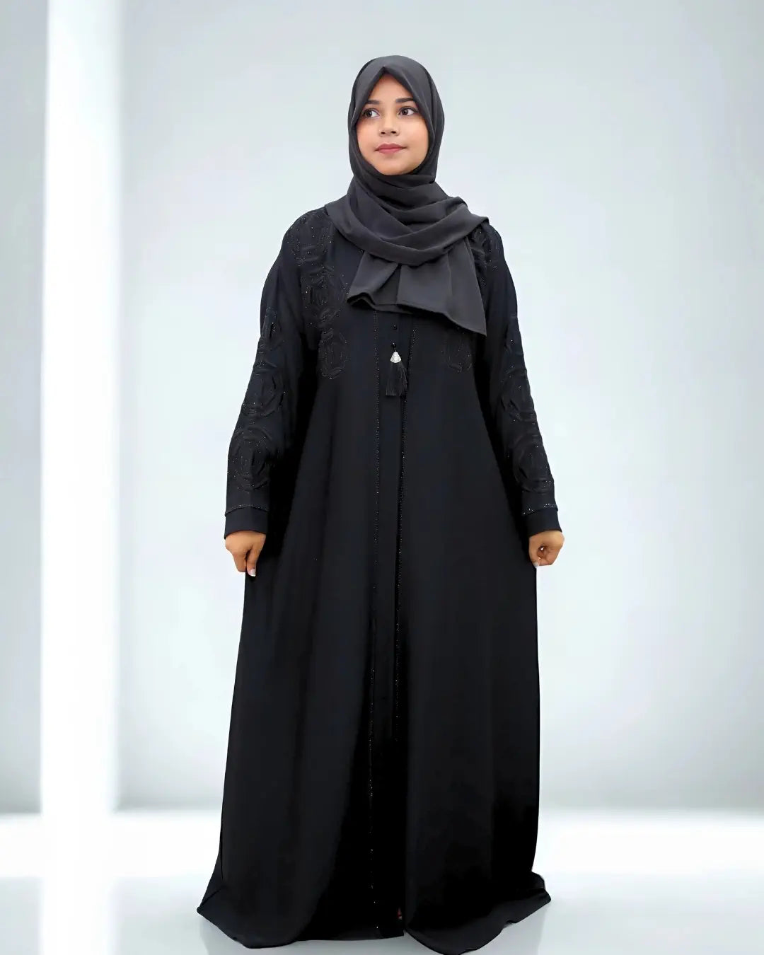 Woman wearing a black abaya and hijab on a white background