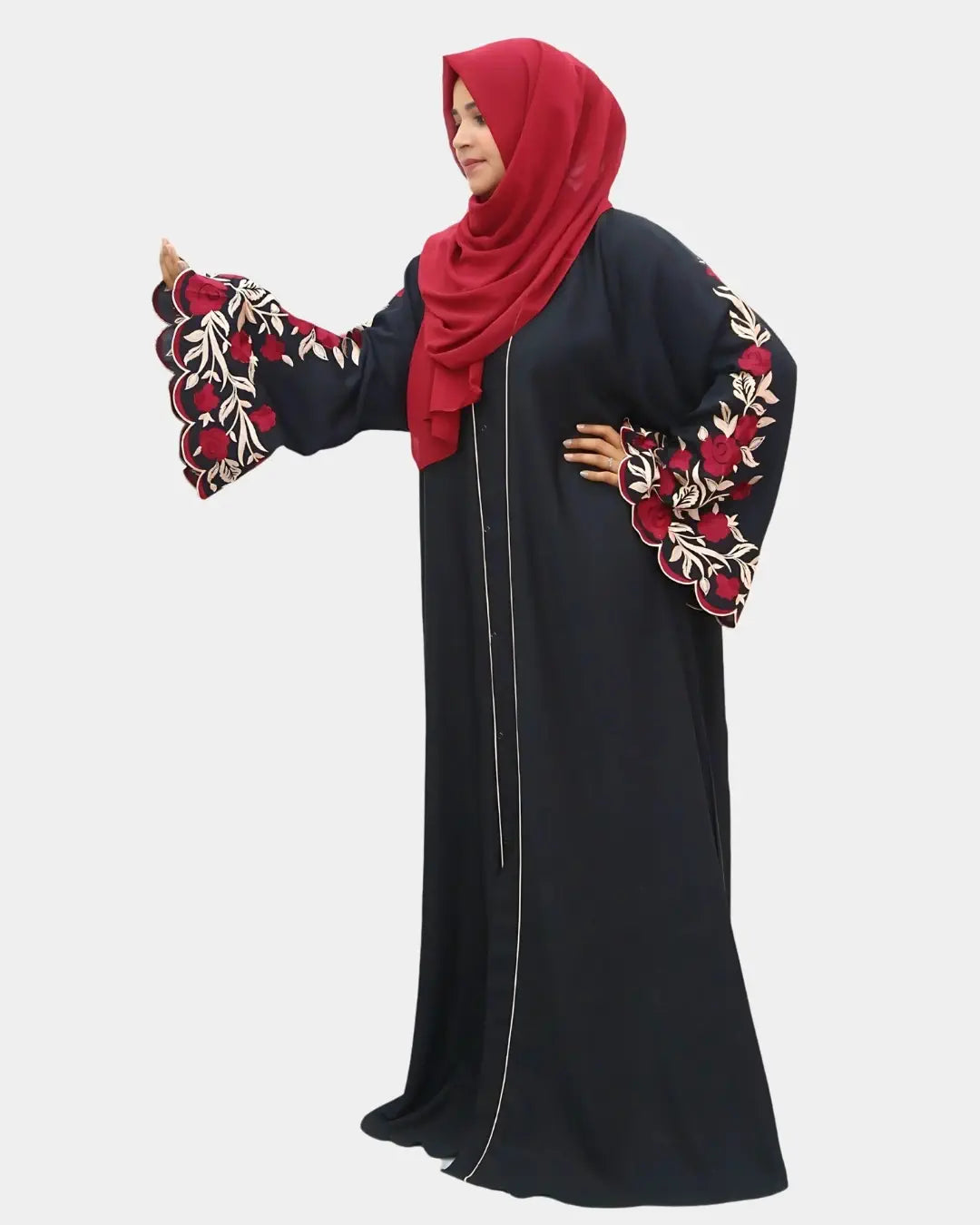 Woman wearing a black abaya with red and gold embroidery and a red hijab on a white background