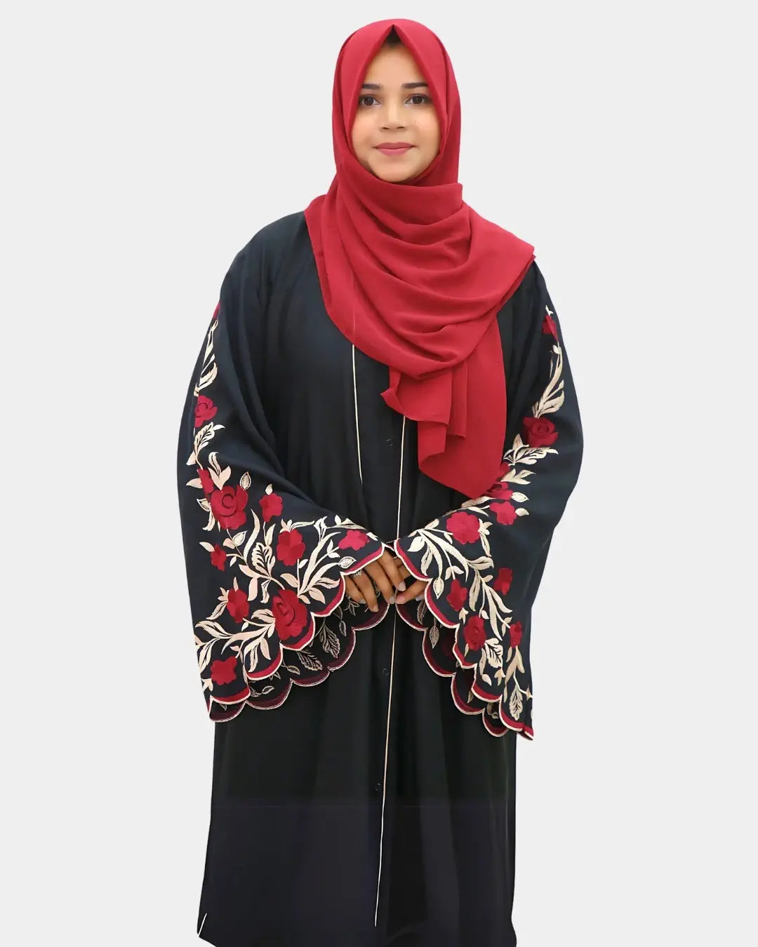 Woman wearing a black abaya with red embroidery and a matching red hijab on a white background