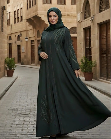 Woman in a dark green abaya walking down a street with traditional architecture.