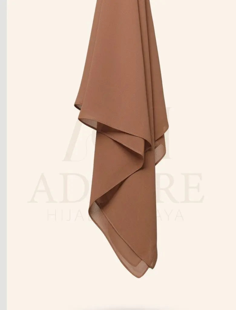 Woman wearing a brown hijab with a plain background