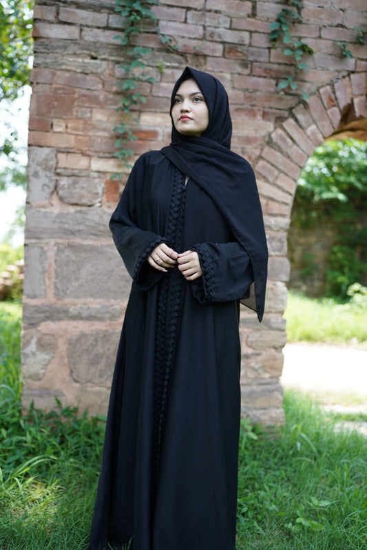 Elegant young woman wearing a black abaya and hijab, showcasing modest fashion style.