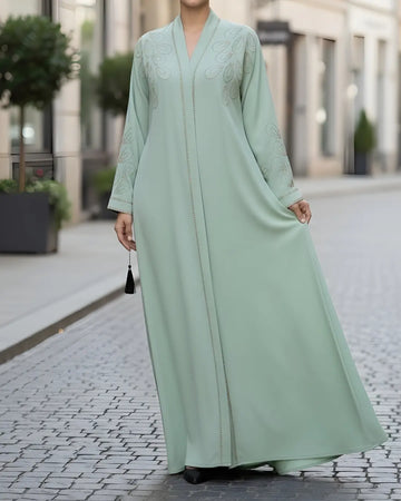 Person wearing a light green abaya on a city street.