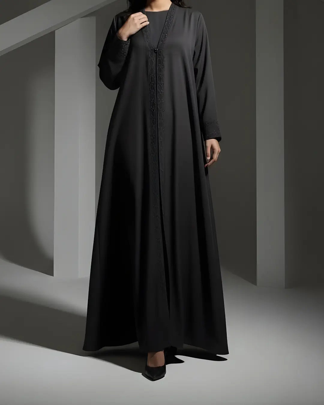 Woman wearing a black ABAYA against a gray background