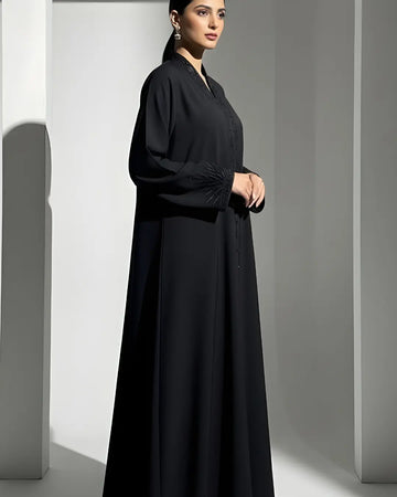 Woman wearing a black ABAYA against a gray background