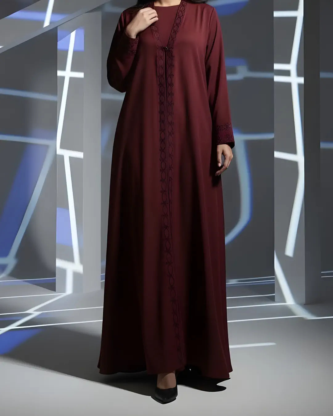 Maroon abaya worn by a person against a modern architectural background