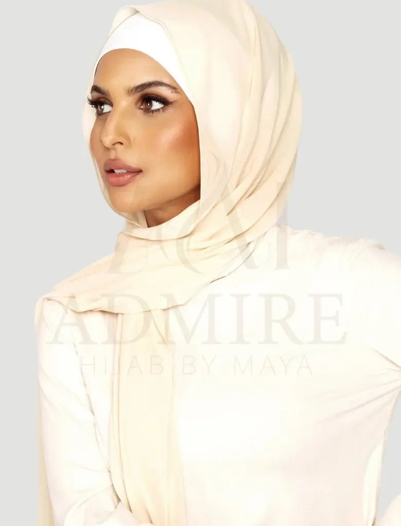 Woman wearing a beige hijab with 'admire hijab' branding on a plain background