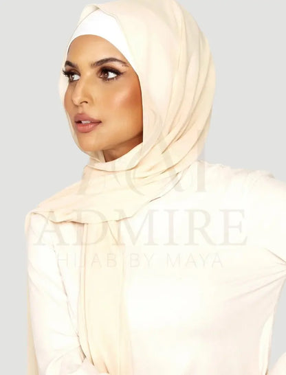 Woman wearing a beige hijab with 'admire hijab' branding on a plain background