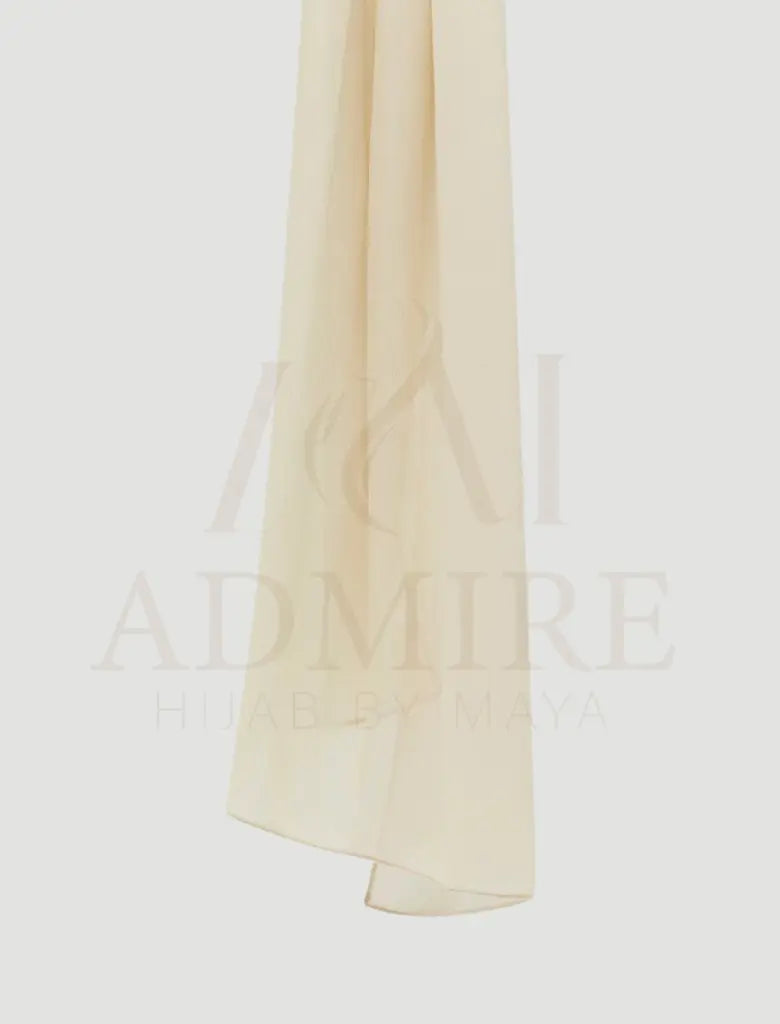 Woman wearing a beige hijab with 'admire hijab' branding on a plain background