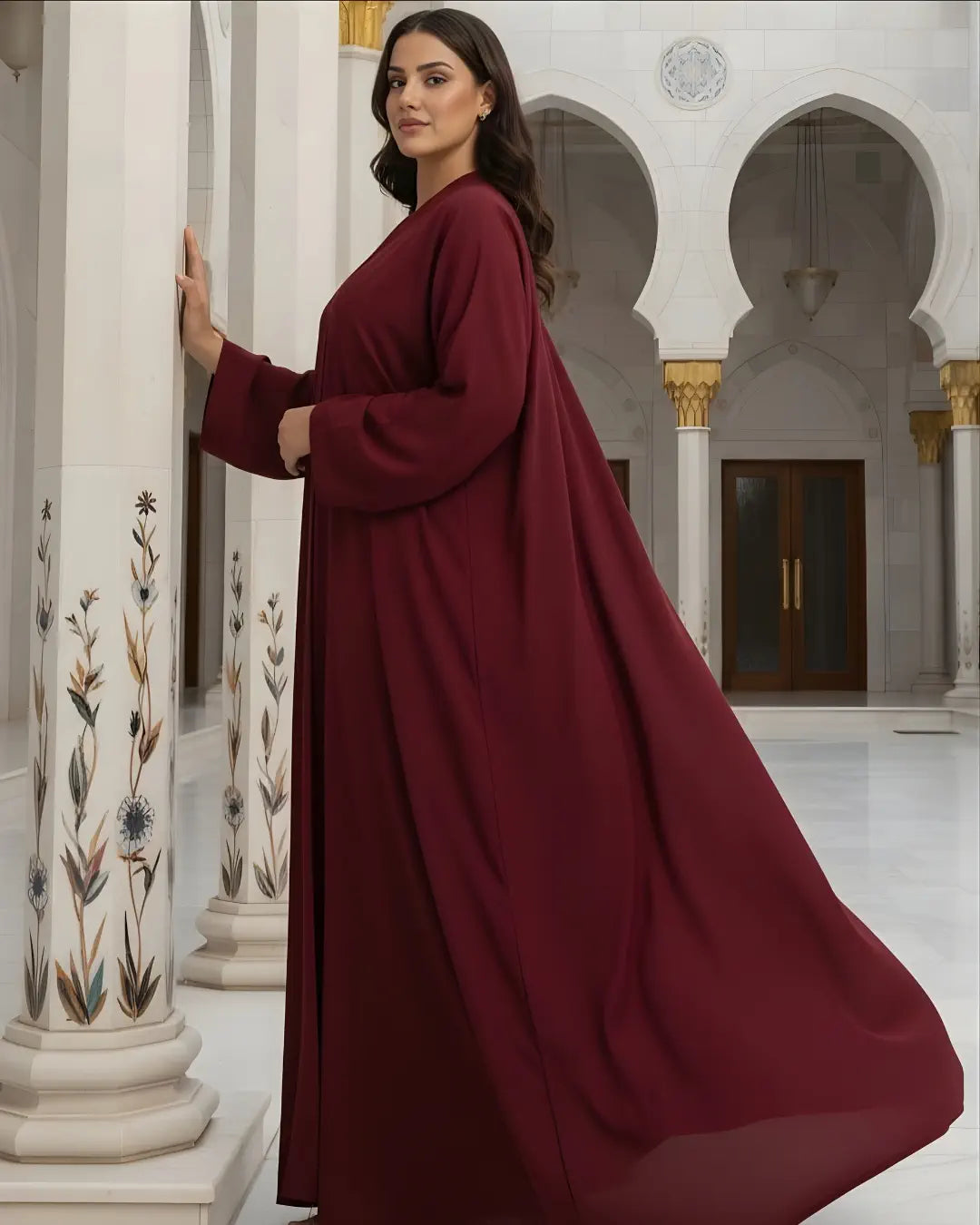 Woman in a burgundy ABAYA standing in a decorated interior setting