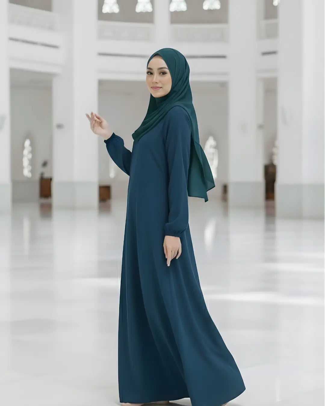 Woman wearing a teal abaya in a white, minimalist setting