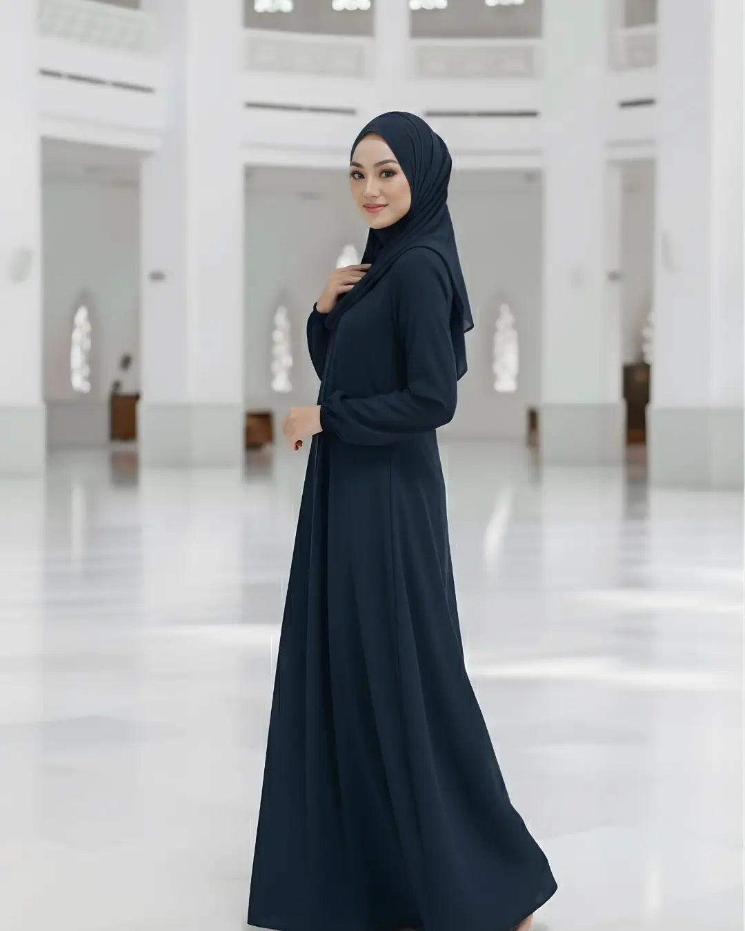 Woman wearing a dark blue abaya in a white, minimalist interior setting