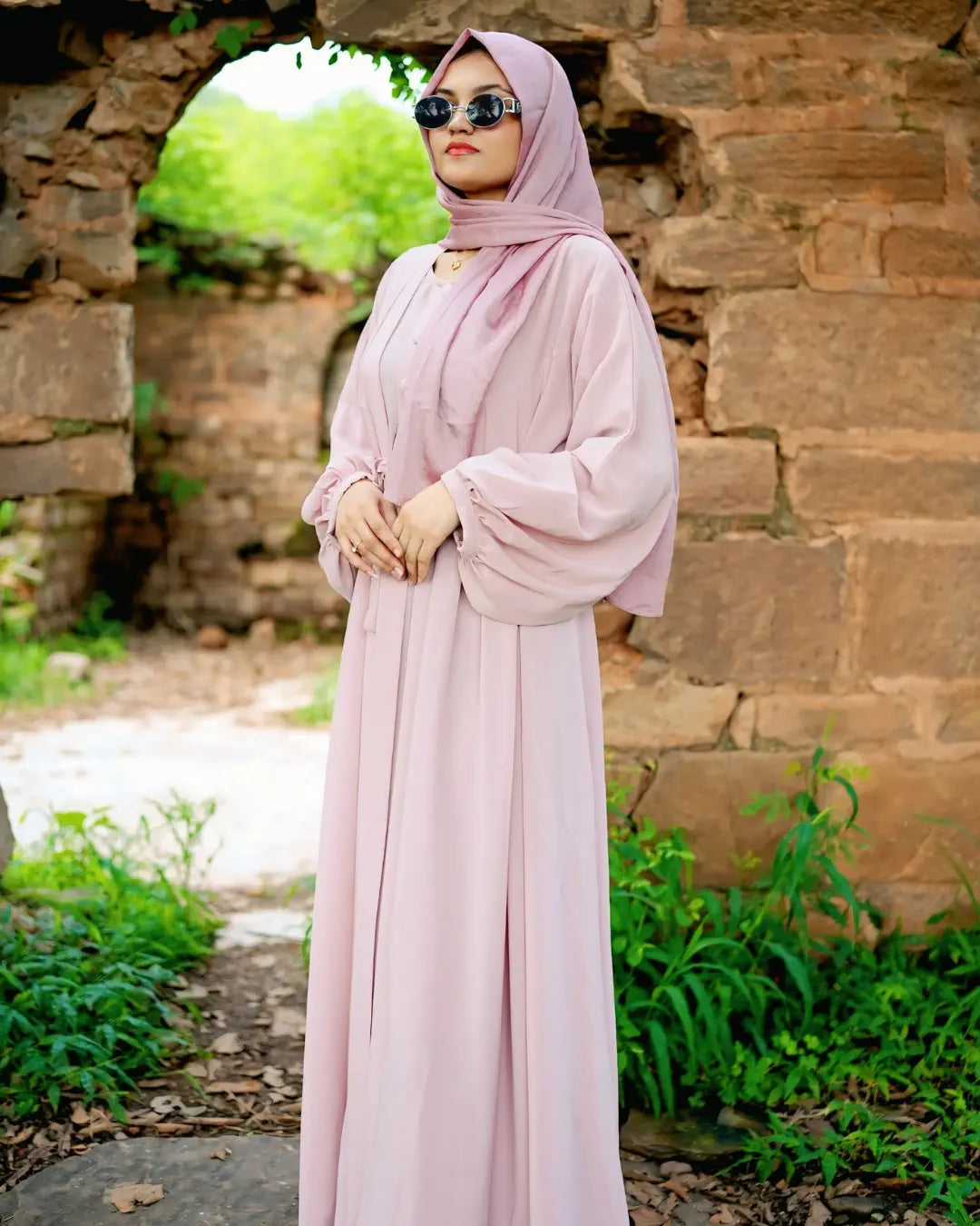 Woman in a long green abaya standing in a park